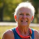 María, una mujer de 67 años con equipación deportiva, sonriendo triunfante tras una carrera